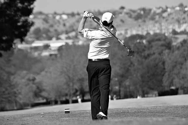 Male golfer in black pants hitting a driver from tee Male golfer in black pants hitting a driver from tee
