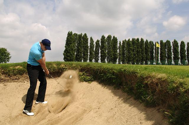 Male golfer in blue hat in a bunker