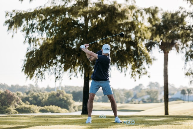 Male golfer in blue shirt swinging driver