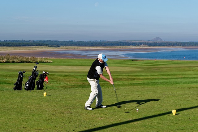 Male golfer in white hat hitting a driver from tee Male golfer in white hat hitting a driver from tee