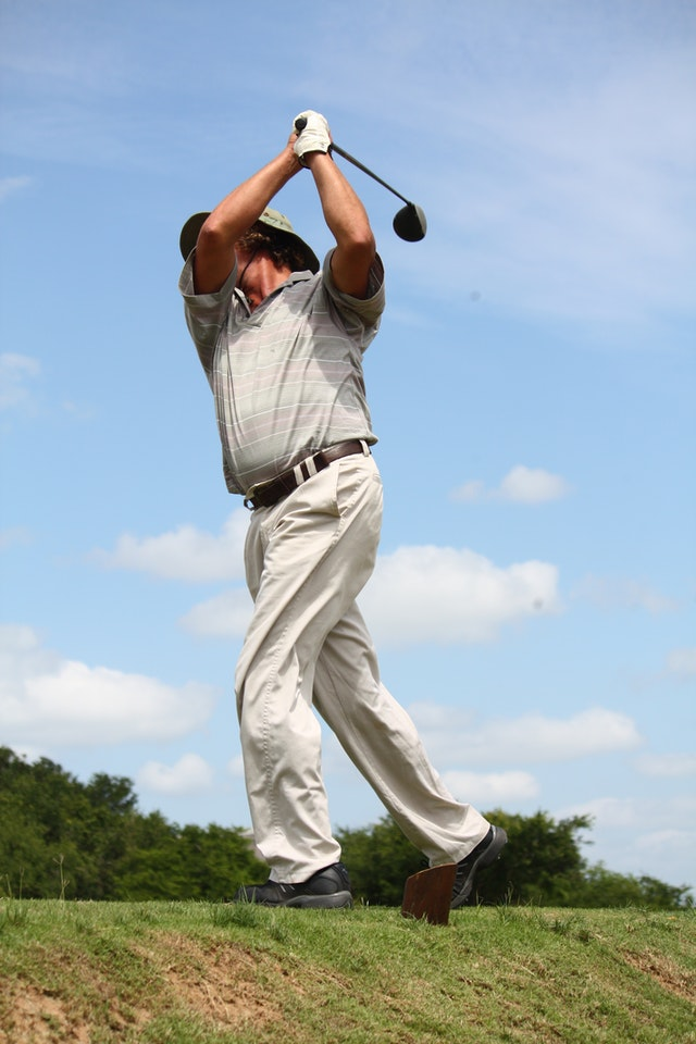 Male golfer in white pants with wood club